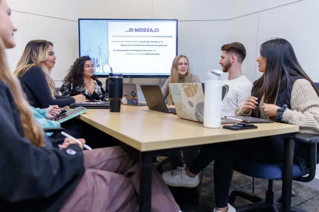 Six physical therapy students sit and talk in a study room