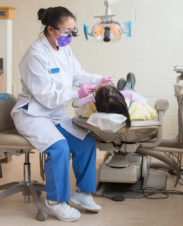 A dental hygiene student performs a teeth cleaning on a patient